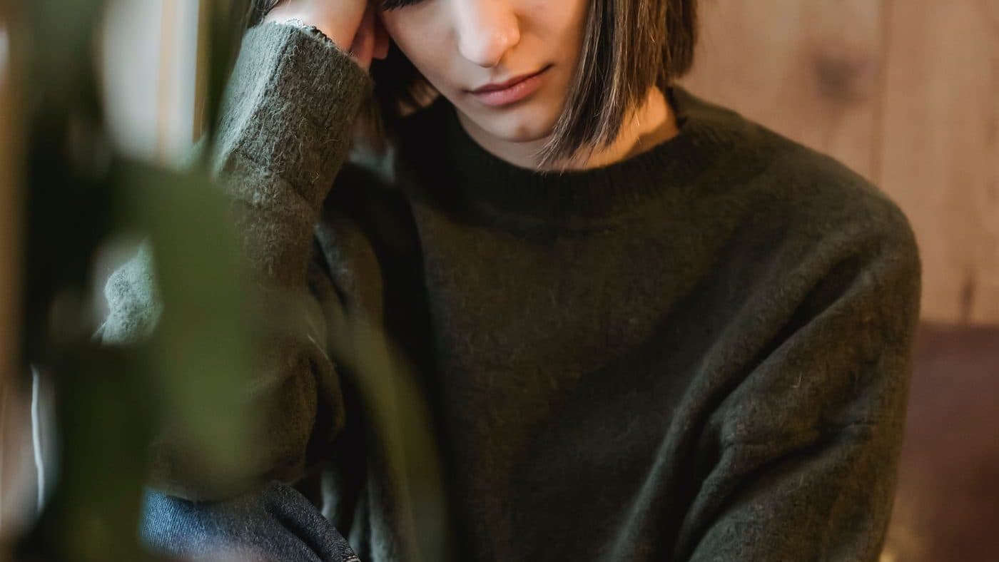 Personne assise, la tête appuyée sur la main, dans une lumière verte tamisée